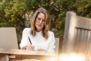 Lady at table writing with a pen