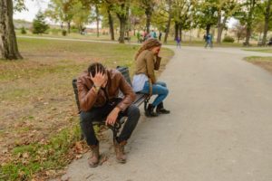 Irritated couple with backs to each other on park bench
