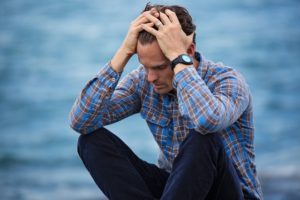 man sitting in plaid shirt touching his hair