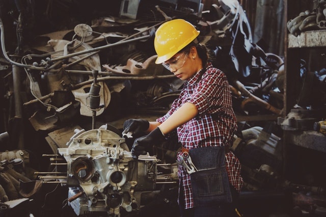 woman in hard hat holding vehicle part