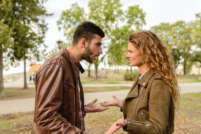 Man and woman in brown jackets breaking up and arguing