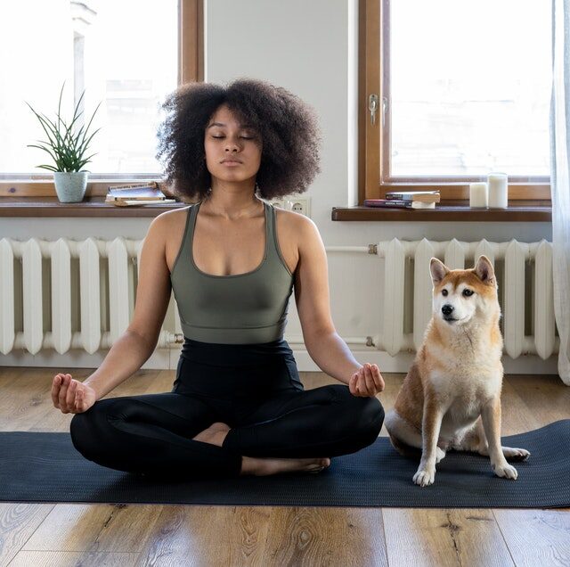 Woman meditating with dog sitting next to her