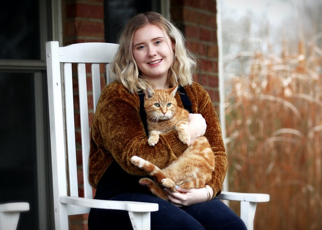 Woman on porch holding a brown cat