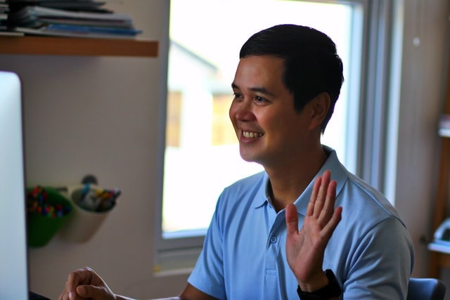 Man holding hand up in online notary meeting